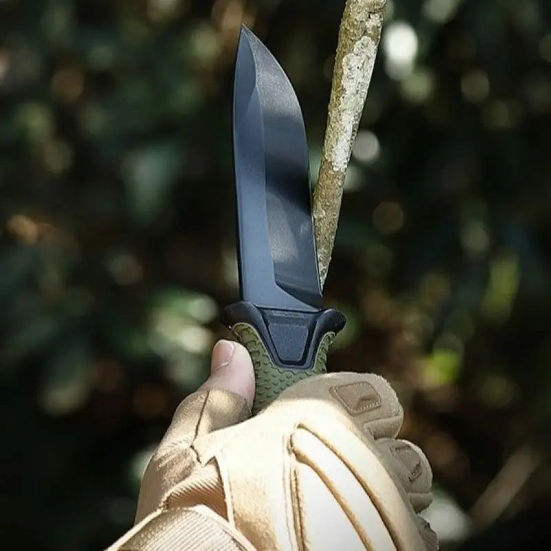 Hand holding a survival knife with a blurred natural background