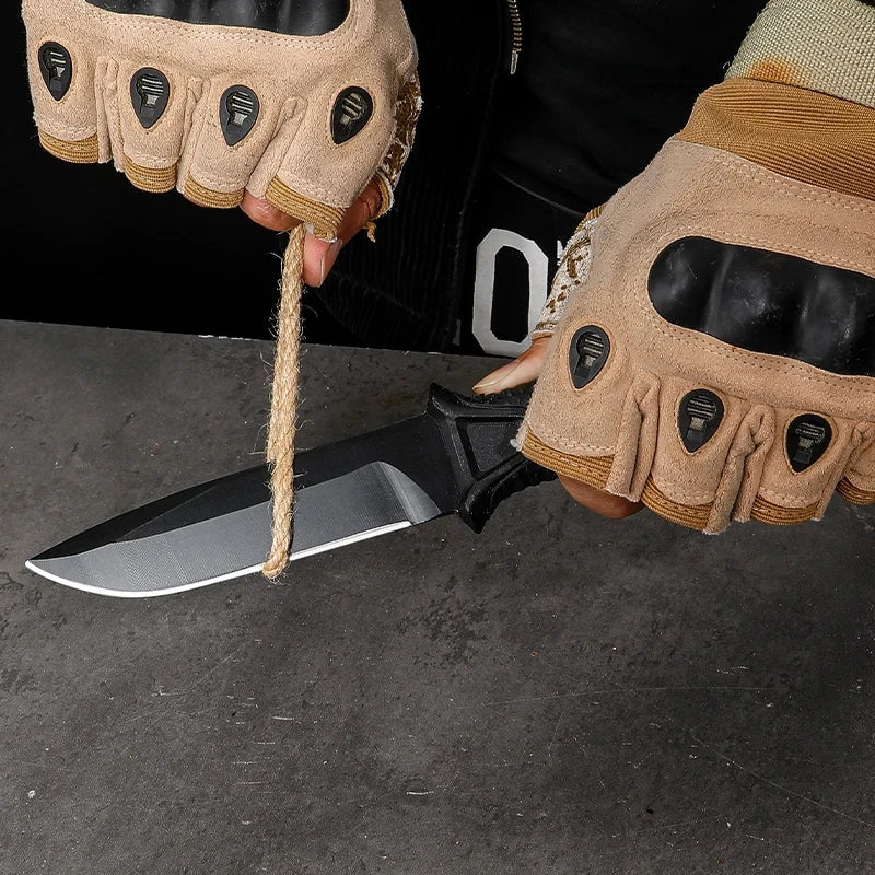 Person wearing tactical gloves holding a knife with a black sheath on a dark surface