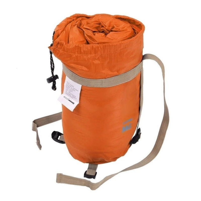 Ultralight sleeping bag in orange with compression straps and shoulder carry