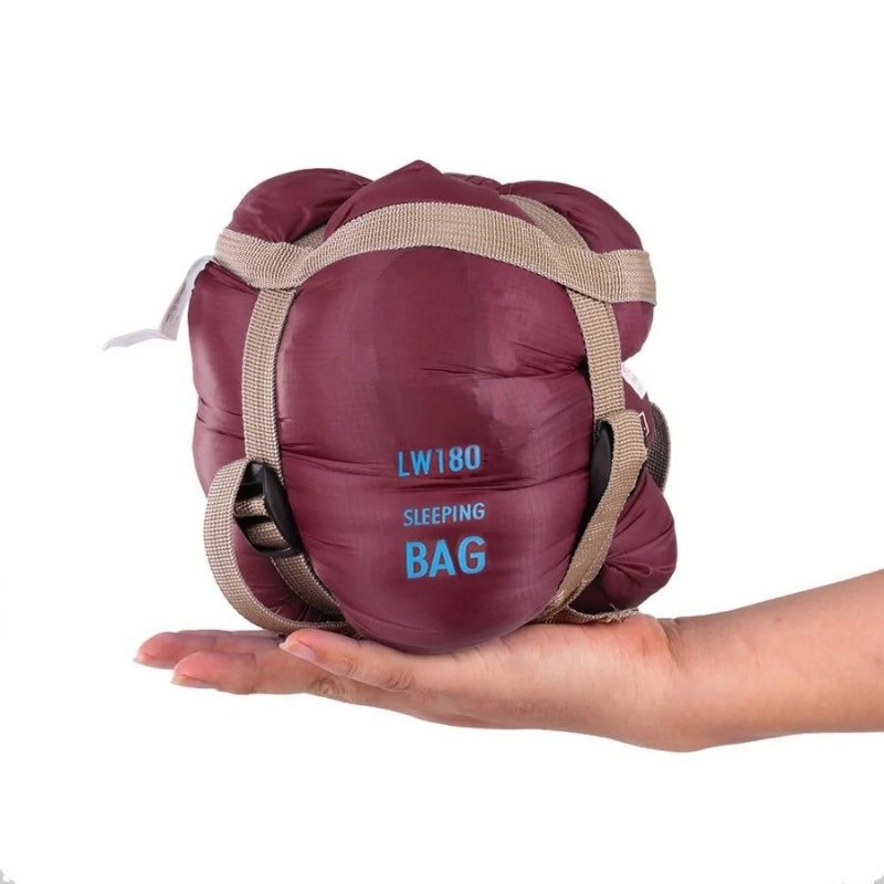 680g ultralight sleeping bag in burgundy compressed, held in one hand