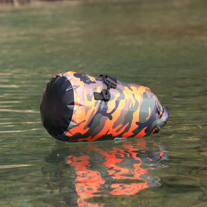 Camouflage waterproof dry bag floating on calm water, demonstrating full water resistance and sealed construction