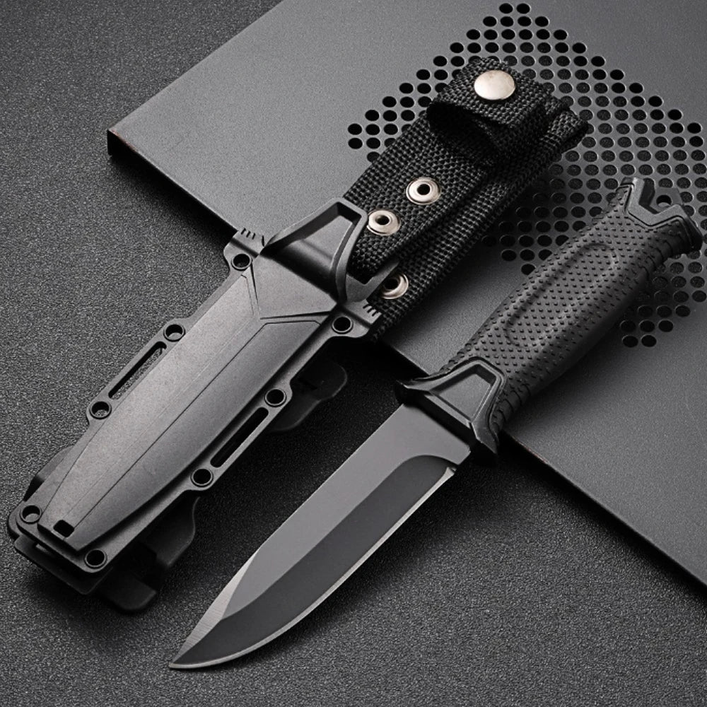 Black tactical camping knife with a textured handle on a dark surface