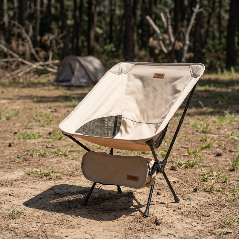Folding camping chair set up at a campsite in beige — portable lightweight beach and camping chair