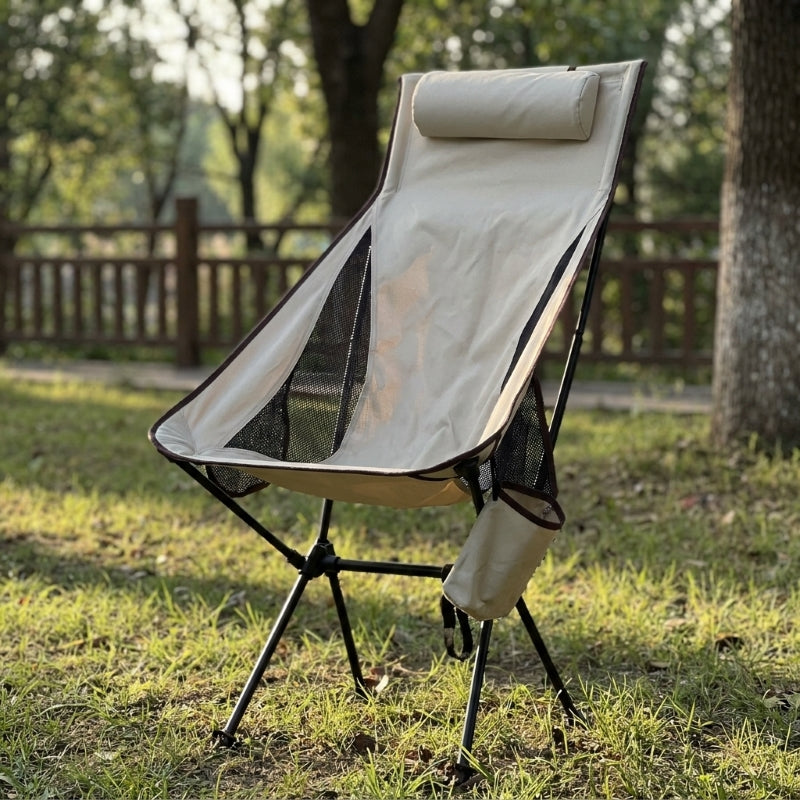 High back folding camping chair in beige standing in outdoor field