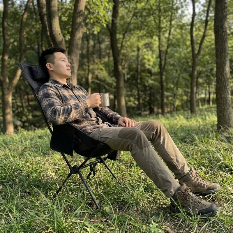 
Man relaxing in high back camping chair outdoors in woodland setting