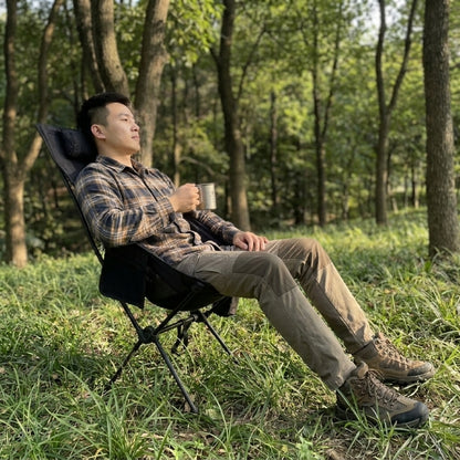 
Man relaxing in high back camping chair outdoors in woodland setting