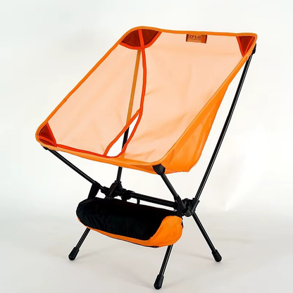 Ultralight camping chair in orange set up outdoors at campsite