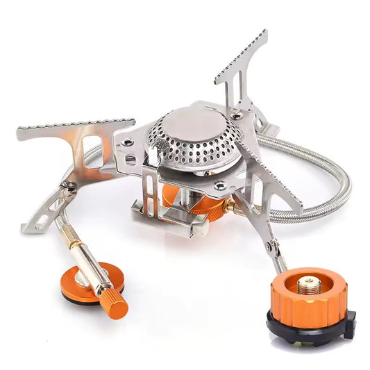 Portable gas camping stove made of metal, featuring three foldable pot supports, a flexible hose, and an orange gas regulator, isolated on a white background.