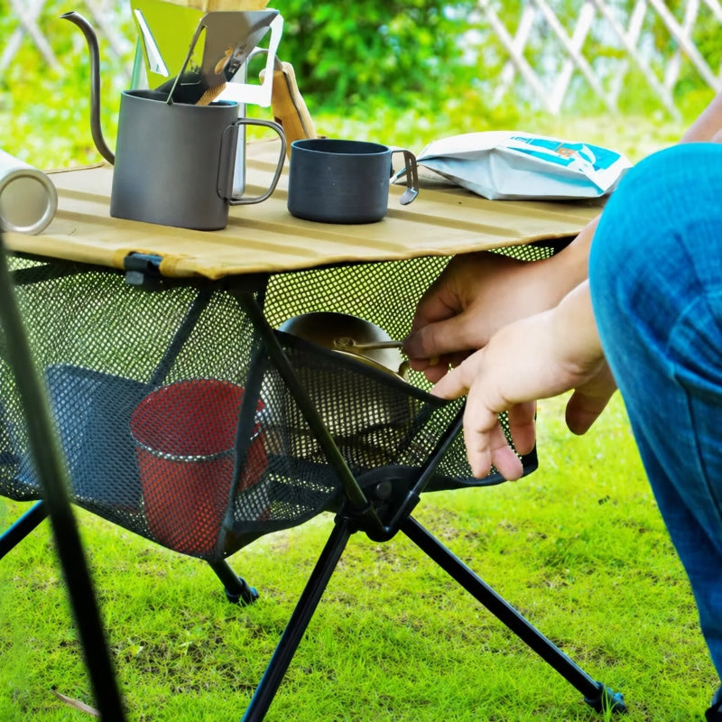 Compact folding camping table set up on grass with camping stove
