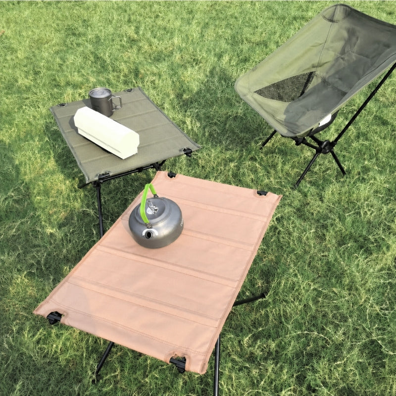 750g folding camping table in olive green set up at forest campsite with camping chair